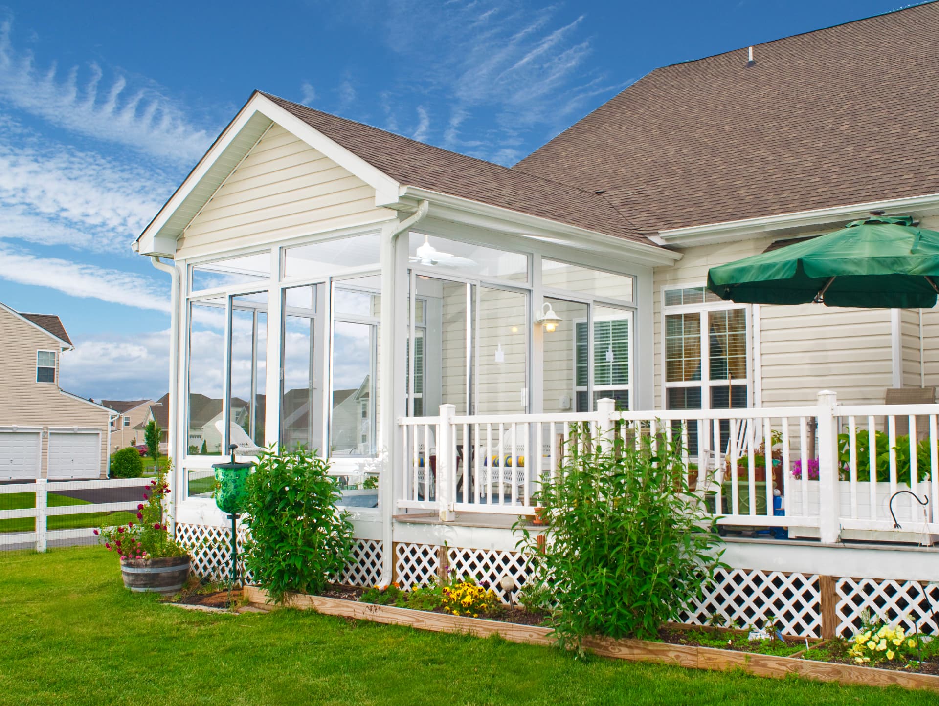 Bright backyard deck with a custom white-framed glass sunroom addition